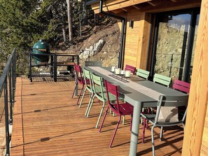 A wooden deck with a table and chairs, a grill, and a view of a rocky hillside. - Brand-new, top-of-the-range chalet with panoramic views (sauna, steam room, billiards) (Les Angles)
