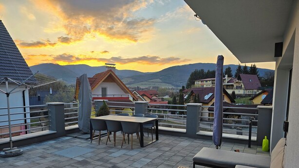 A terrace with a table and chairs, a small table, and a sofa.
