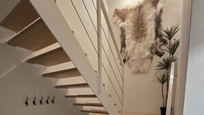 A modern staircase with wooden steps and white railings, a mounted animal head on the wall, and a potted plant on the landing.