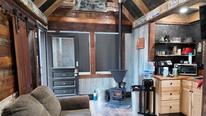 A cozy cabin interior with a living area featuring a couch and a kitchen equipped with a stove, microwave, and various appliances.