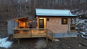 A cabin with a wooden deck, a small porch, and a metal roof.