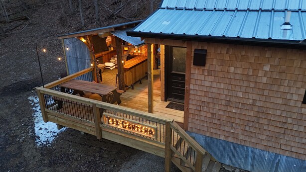 A rustic cabin with a wooden deck, a kitchen area, and a sign indicating 'Factory Parking'.