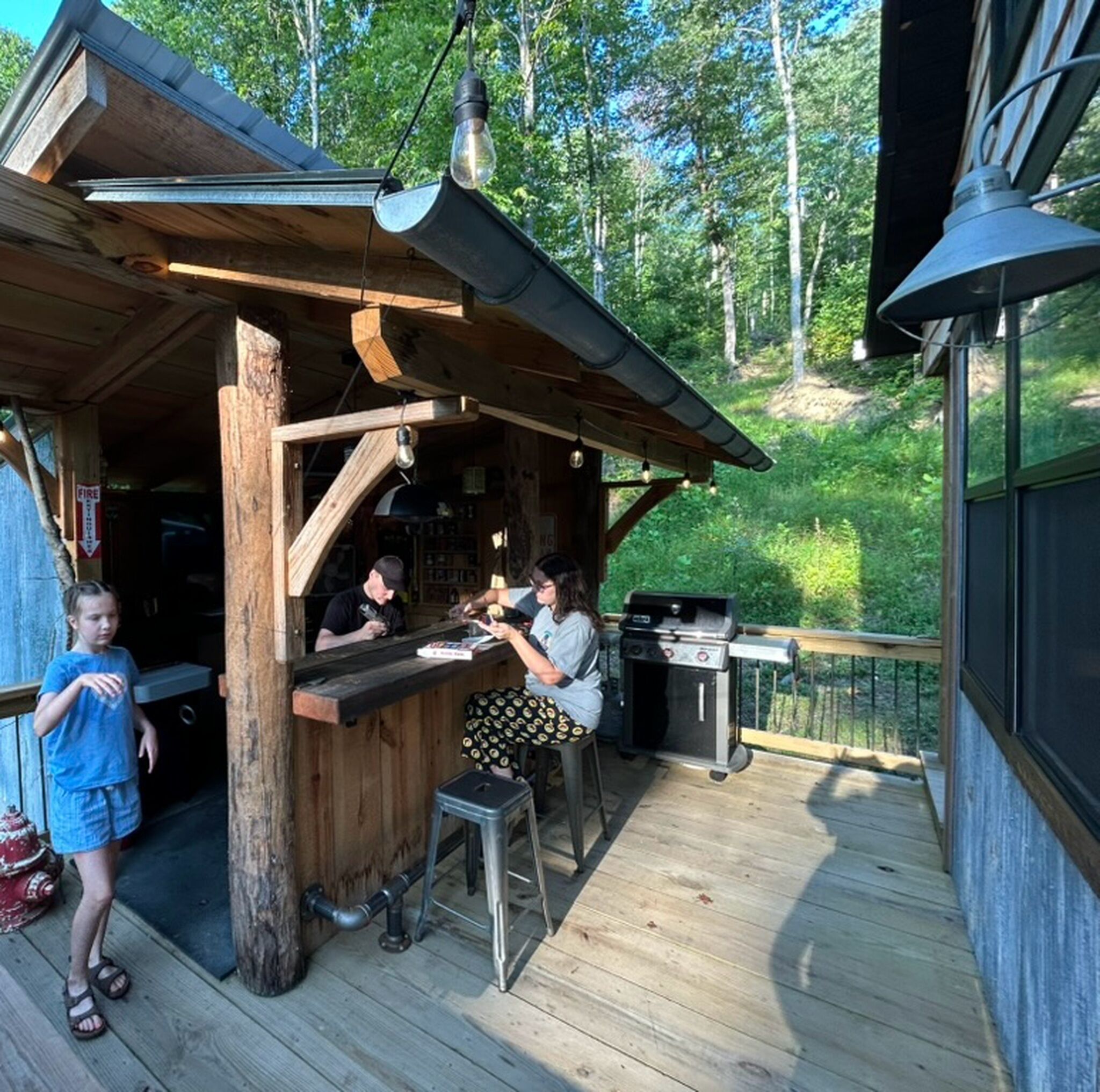 A wooden outdoor seating area with a grill and a fire extinguisher.