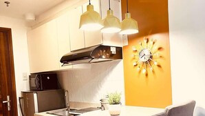A modern kitchen with a central island, pendant lights, a built-in stove, and a wall clock. - Sassy and Classy Fully Furnished Studio Unit located Cebu City Centre (Cebu City)
