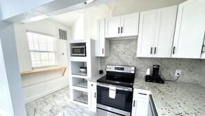 A modern kitchen with white cabinets, a stainless steel oven, a microwave, and a coffee maker. - WATERFRONT 2bd/1ba Apartment w/ Kayaks (St. Petersburg)