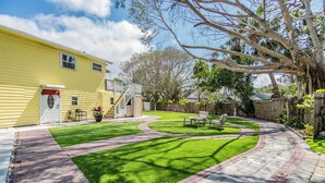 A well-maintained backyard with a paved patio, a grassy lawn, and a wooden deck. - WATERFRONT 2bd/1ba Apartment w/ Kayaks (St. Petersburg)
