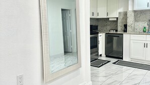 A modern kitchen with white cabinets, a large mirror, and a marble floor. - WATERFRONT 2bd/1ba Apartment w/ Kayaks (St. Petersburg)