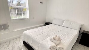 A bedroom with a bed, white bedding, a window with blinds, and a ceiling light. - WATERFRONT 2bd/1ba Apartment w/ Kayaks (St. Petersburg)