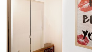 Een kamer met een garderobe, een klein bankje en een muur met een rode lippenstiftafdruk.