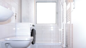 Een moderne badkamer met toilet, wasmachine en douche.