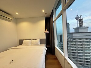 Una habitación de hotel moderna con una cama grande, vistas a un paisaje urbano y una ventana con cortinas.