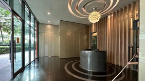 A modern lobby with a circular reception desk, a mop, and a unique ceiling design.