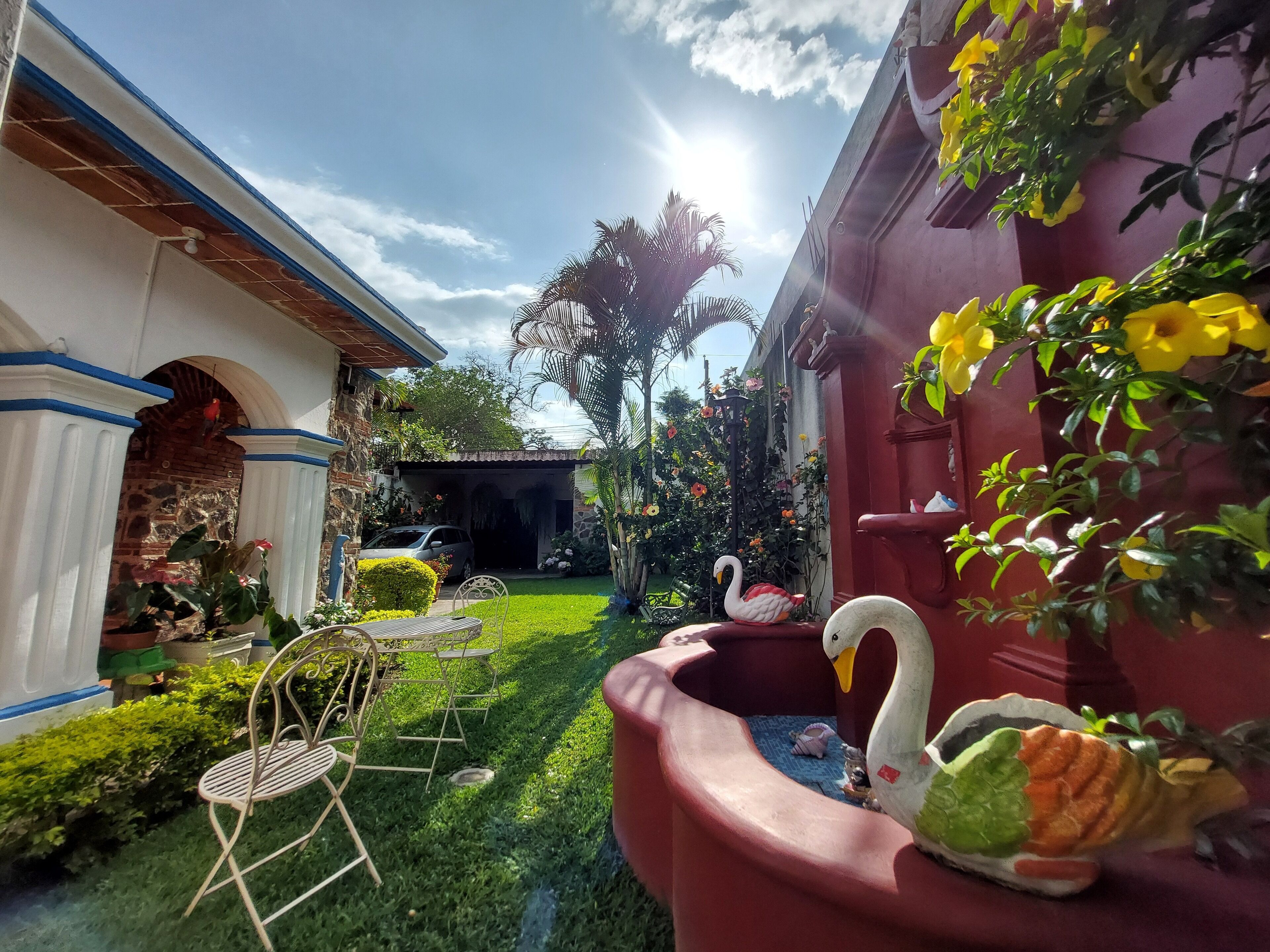 A garden with a swan sculpture, a car, and a patio chair.
