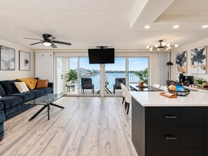 A modern living room with a sofa, coffee table, and a balcony with a view. - Bayfront 2BR by Convention Center + Sunsets (Ocean City)
