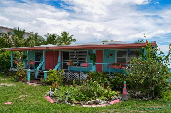 Une maison avec un porche, un petit jardin et un toit rouge.