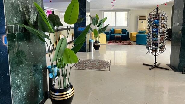 Een ruime lobby met een moderne kroonluchter, een zithoek met banken en een decoratieve plantenpresentatie.