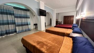 Een hotelkamer met twee bedden, een televisie en een eethoek met een rode tafelkleed.