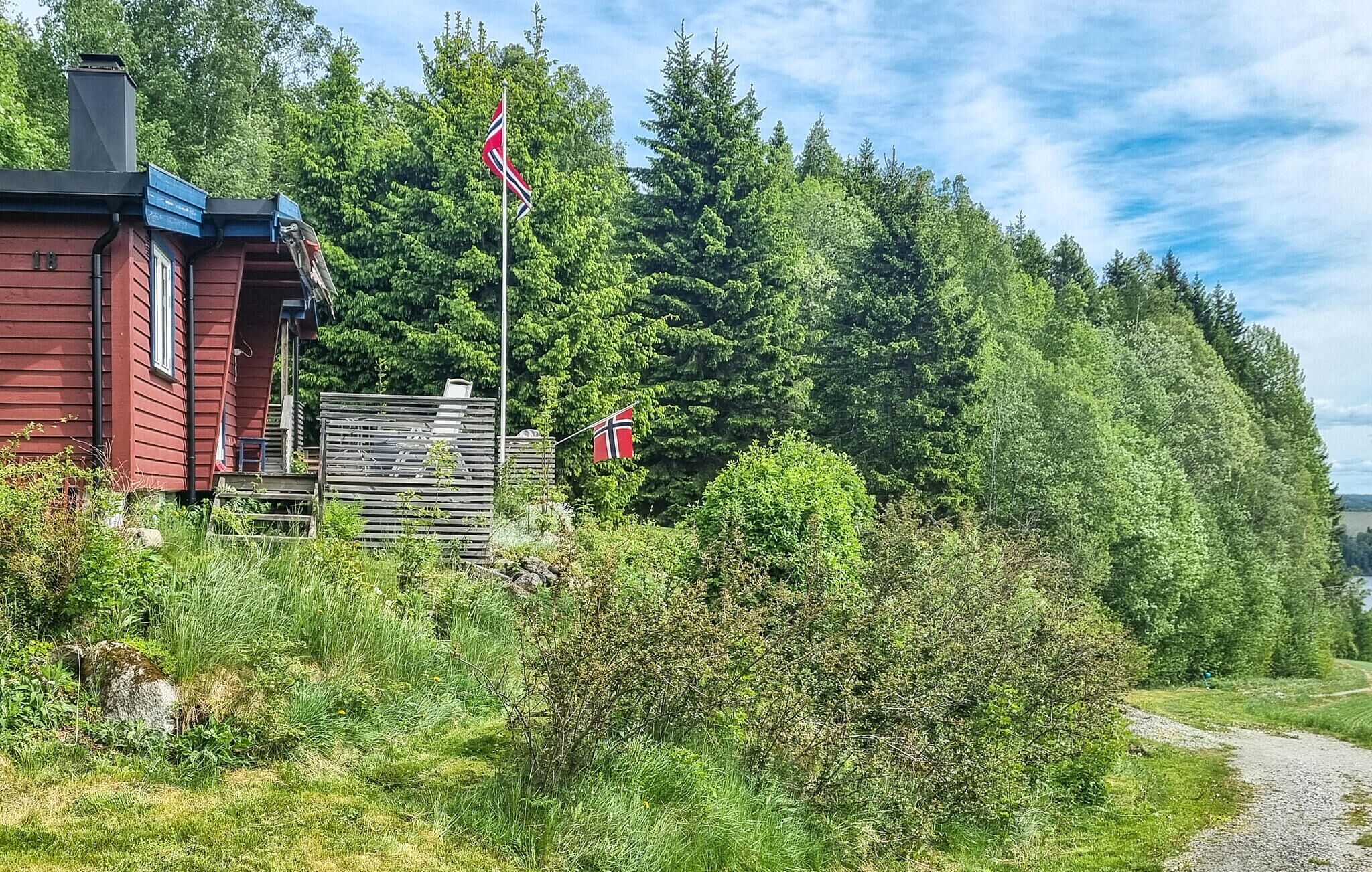 Een rood gebouw met een vlag, omgeven door weelderige begroeiing en een grindpad.