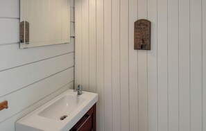 A bathroom with a white sink, wooden cabinet, and a mirror.