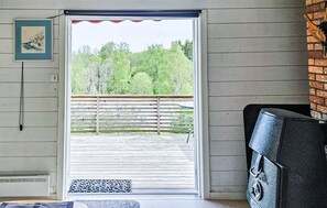 A room with a wooden floor, a door leading to an outdoor deck, a black chair, and a framed picture on the wall. - 2 bedroom lovely home in Enebakk (Enebakk)