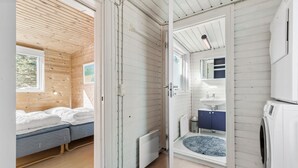 A cozy cabin with a wooden interior, a bed, a bathroom with a sink and mirror, and a washing machine. - 3 bedroom awesome home in Ebeltoft (Ebeltoft)