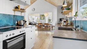 A modern kitchen with a wooden ceiling, white cabinetry, and a dining area with a wooden table and chairs. - 3 bedroom awesome home in Ebeltoft (Ebeltoft)