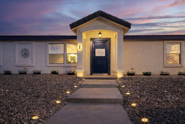 A building with a dark entrance door, a small porch, and a pathway leading to the door.