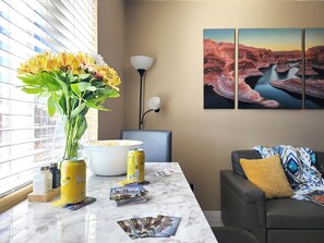 A modern living room with a marble countertop, a vase of flowers, a lamp, and a couch with a patterned throw.