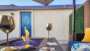 A patio area with a fire feature, two wine glasses, and a door labeled "Diana Guesthouse".