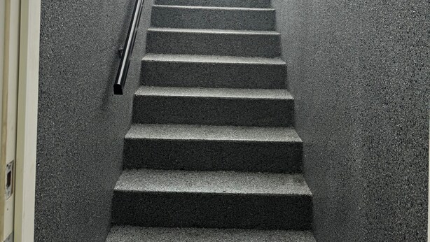 Eine Treppe führt zu einem überdachten Bereich mit Metallgeländer.