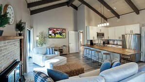 A spacious living area with a fireplace, a sofa, and a kitchen with a bar.