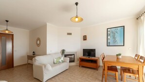 Una sala de estar con sofá, televisor, mesa de comedor y sillas.