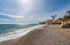 A pebbled beach with a rocky cliff and a building with a red roof. - Amazing home in Vinaroz (Vinaroz)