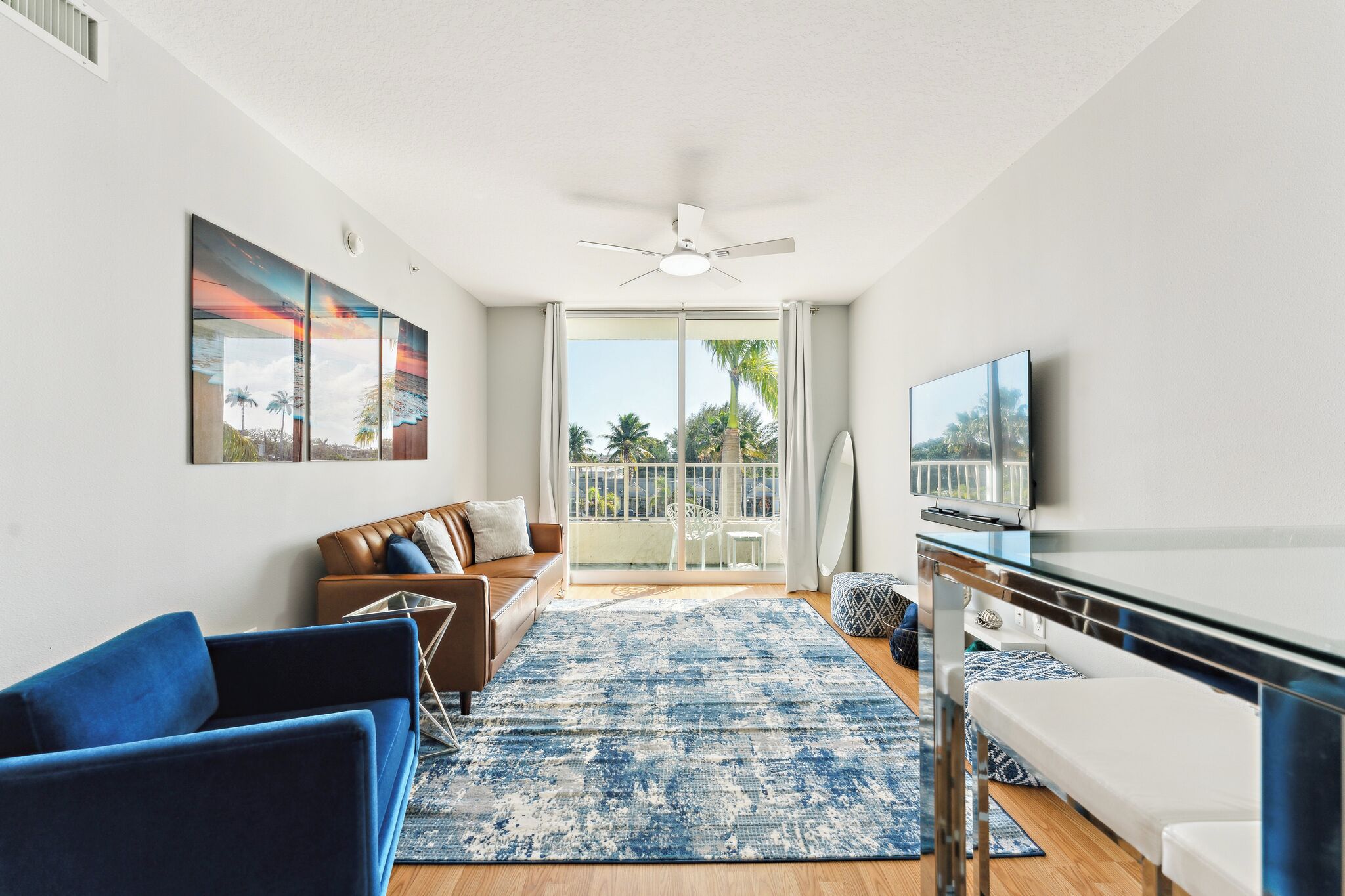 A modern living room with a sofa, blue armchairs, a coffee table, and a TV.