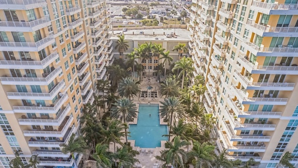 Un hôtel de grande hauteur doté de nombreux balcons, d’une piscine centrale entourée de palmiers et d’une cour intérieure.