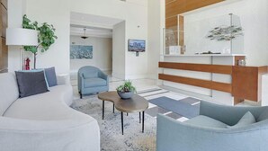 Ein modernes Wohnzimmer mit einem weißen Sofa, einem blauen Sessel, einem Couchtisch mit Pflanze und einer Wand aus Holz.
