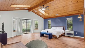 A bedroom with a wooden ceiling, a bed, a desk, and a chair.