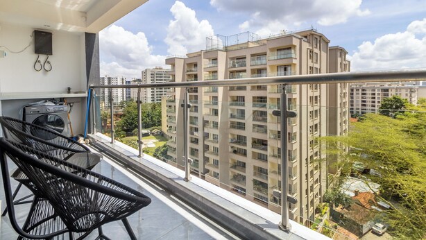 Un balcón con vistas a edificios altos, una lavadora y una silla.
