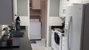 A compact kitchen with white cabinets, a built-in oven, a refrigerator, and a microwave.