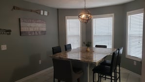 A dining area with a marble table, black chairs, and a hanging light fixture.