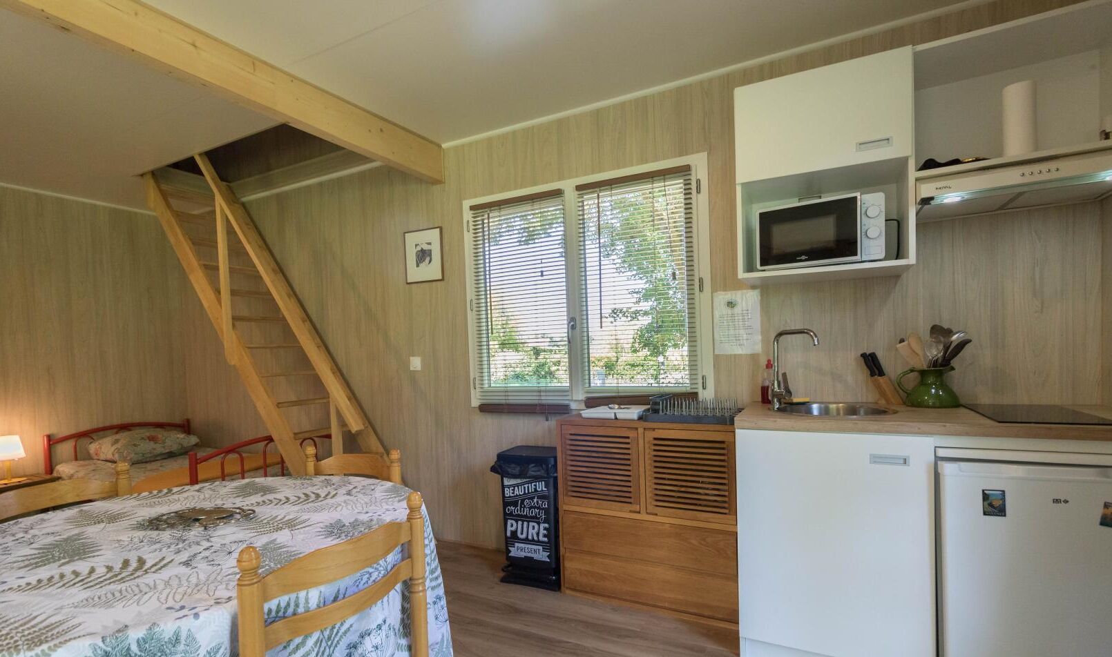 Ein kleines Zimmer mit Bett, einer Küchenzeile, einer Mikrowelle, einem Spülbecken und einem kleinen Kühlschrank.