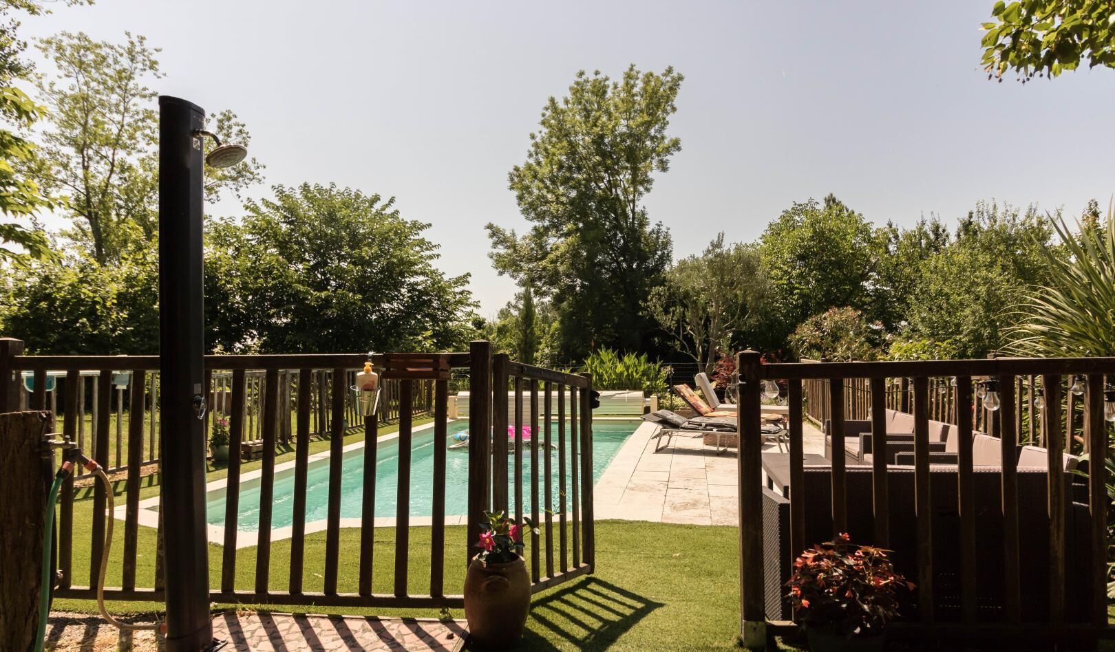 Ein Garten mit Swimmingpool, Holzterrasse und einem verschlossenen Eingang.