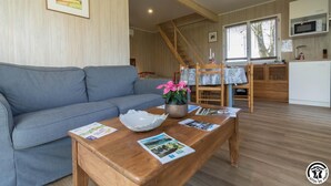 A modern living room with a grey sofa, wooden coffee table, and a staircase leading to an upper level. - Les Collines du Pastel (VERFEIL)