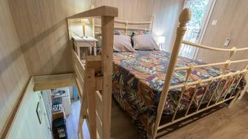 Une chambre à coucher avec un cadre de lit en bois, une couvre-lit colorée et une petite table de chevet avec une lampe.