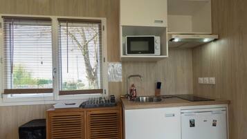 A compact kitchen with a microwave, sink, and a small refrigerator.