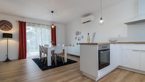 Une cuisine moderne avec des meubles blancs, un four encastré et un plan de travail en bois.