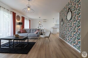 A modern living room with a grey sofa, a black coffee table, and a patterned wall.