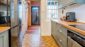 Una cucina con frigorifero, macchina del caffè e finestra con persiane.