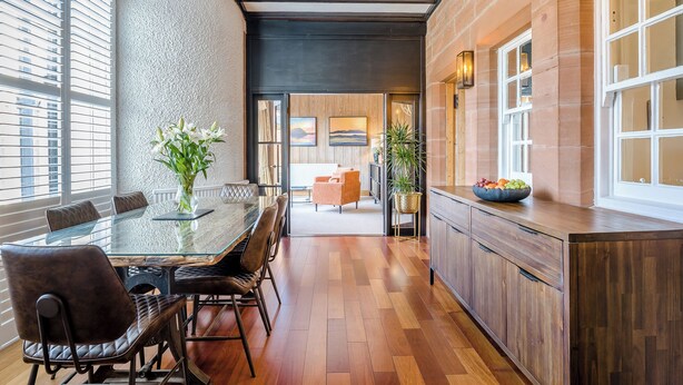 Una cucina moderna con un tavolo da pranzo in vetro, mobili in legno e vista sull'area soggiorno.