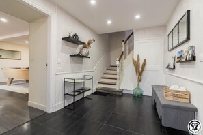 Stairs lead to an upper level, with a vanity and mirror below, and a bench against the wall.
